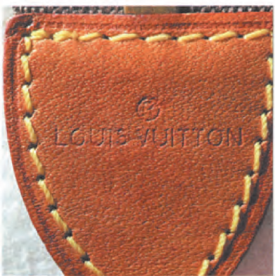 Spotting Fake Designer Bags-close - up of a shield - shaped leather tag from a Louis Vuitton bag, with embossed "LOUIS VUITTON" visible, and without country.