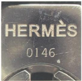 Close-up of Hermès lock and key hardware with "HERMES" and "0146" engraving – showcasing precision metal craftsmanship.